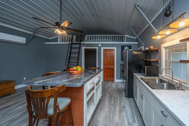 kitchen featuring sink, vaulted ceiling, hardwood / wood-style flooring, ceiling fan, and white cabinetry