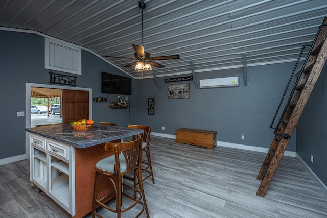 kitchen with a wall mounted air conditioner, a kitchen bar, vaulted ceiling, ceiling fan, and hardwood / wood-style flooring