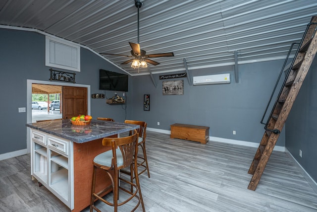 kitchen with ceiling fan, a wall unit AC, wood-type flooring, lofted ceiling, and a kitchen bar