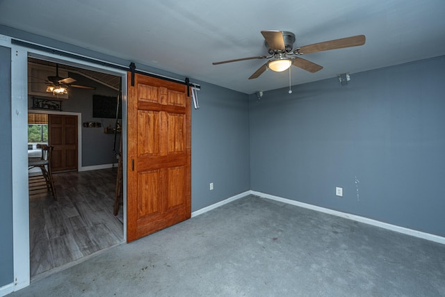 unfurnished bedroom with ceiling fan, a barn door, and carpet floors