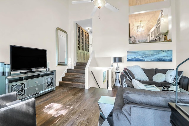 living room with ceiling fan, a towering ceiling, and dark hardwood / wood-style floors