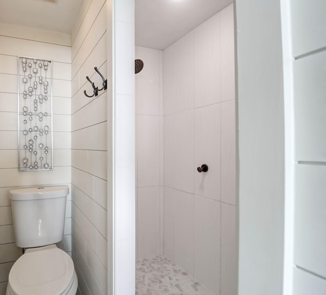 bathroom with a tile shower and toilet