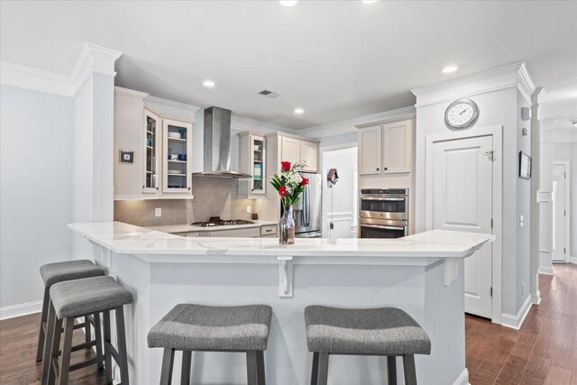 3751 Copahee Sound Dr, Mount Pleasant, SC 29466 - kitchen with wall chimney range hood, appliances with stainless steel finishes, a peninsula, decorative backsplash, and a breakfast bar