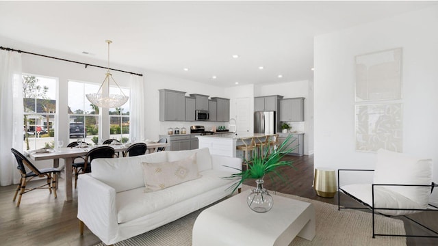 living room with dark hardwood / wood-style flooring, an inviting chandelier, and sink