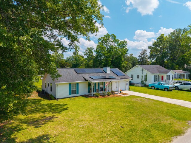 171 N Main St, Ridgeville, SC 29472 - ranch-style home with concrete driveway, a garage, roof mounted solar panels, a front yard, and central air condition unit