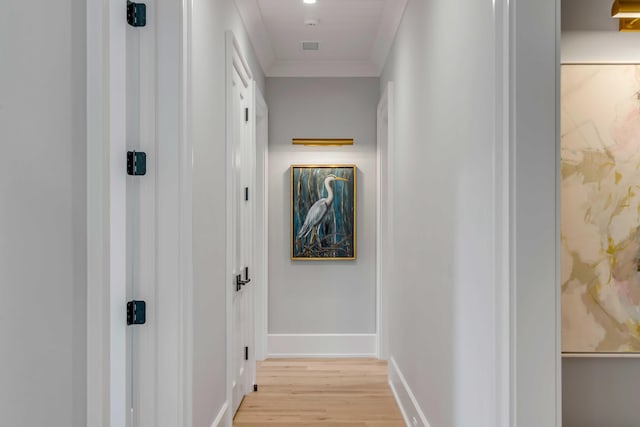 corridor featuring light wood-type flooring, baseboards, and crown molding