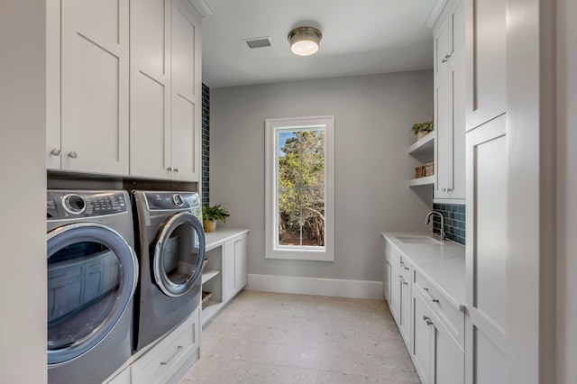 laundry area with washer and clothes dryer, visible vents, cabinet space, a sink, and baseboards