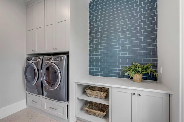 clothes washing area featuring washer and clothes dryer and cabinet space