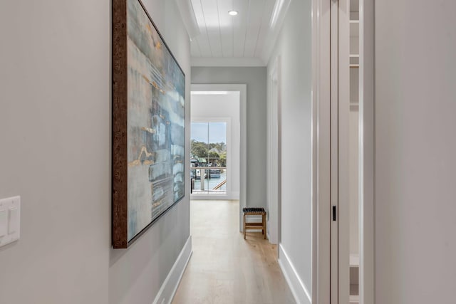 corridor with ornamental molding and light wood-style flooring