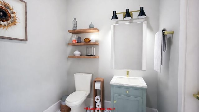 half bath featuring toilet, vanity, and baseboards