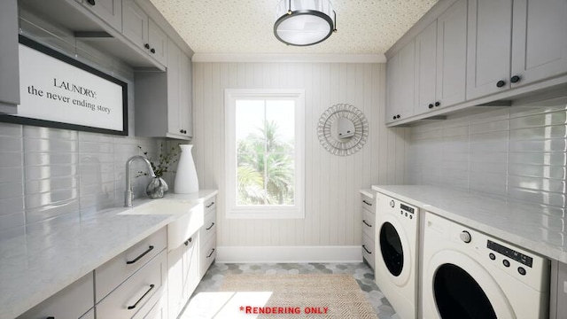 clothes washing area featuring cabinet space, baseboards, washing machine and clothes dryer, crown molding, and a sink