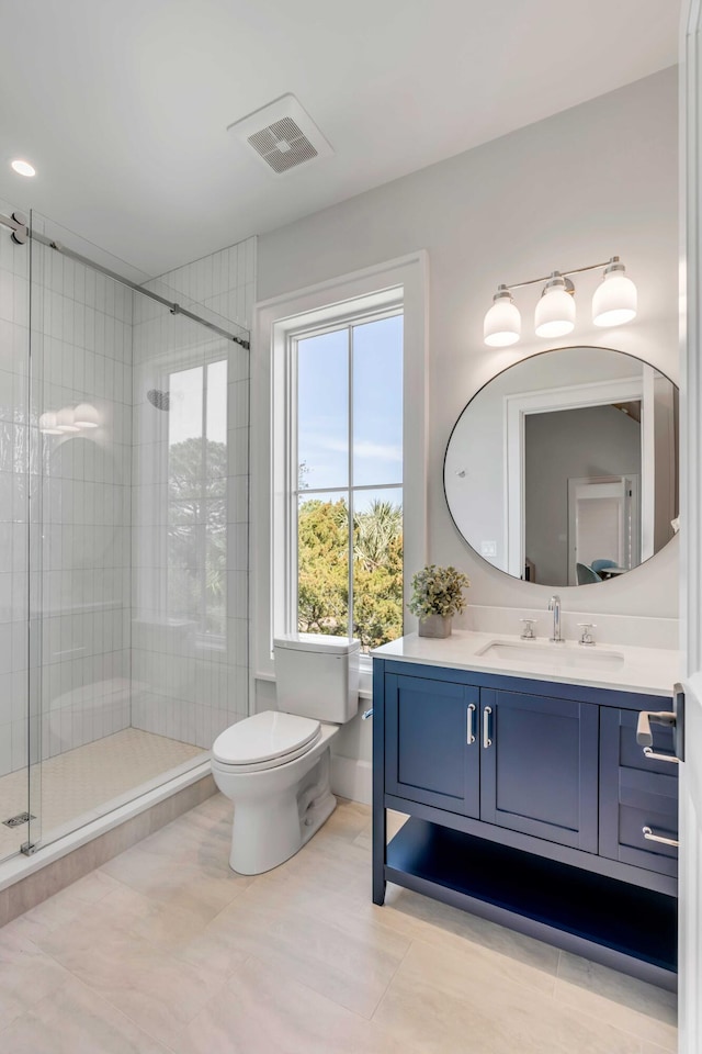 bathroom featuring tile patterned flooring, toilet, vanity, visible vents, and a stall shower