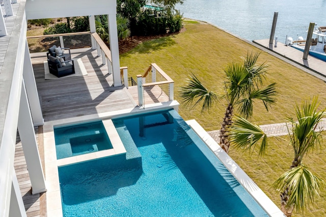 view of swimming pool with a lawn, a water view, and a pool with connected hot tub