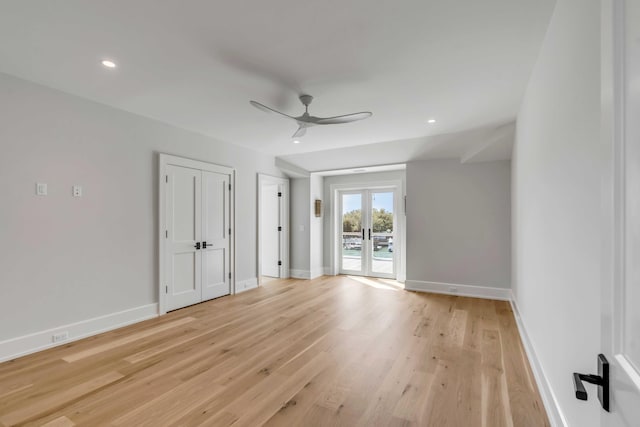 empty room with ceiling fan, french doors, light wood-style floors, and baseboards