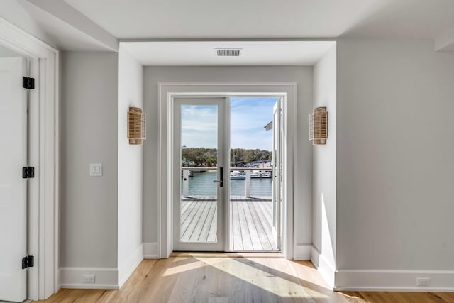 doorway with visible vents, light wood-style flooring, and baseboards