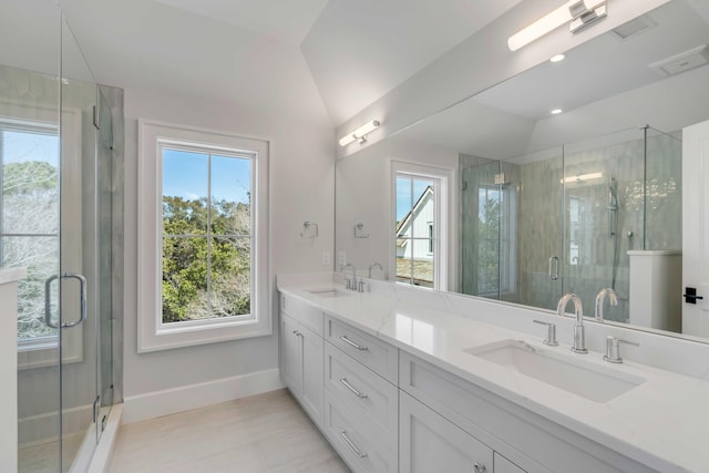 full bathroom with a stall shower, lofted ceiling, a sink, and double vanity