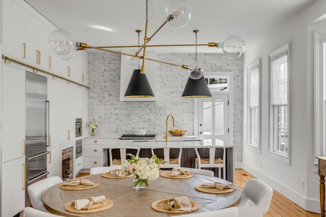 kitchen with sink, white cabinetry, stainless steel built in refrigerator, wine cooler, and light hardwood / wood-style floors