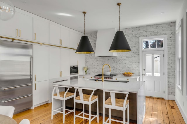 kitchen featuring white cabinetry, appliances with stainless steel finishes, a kitchen island with sink, and pendant lighting