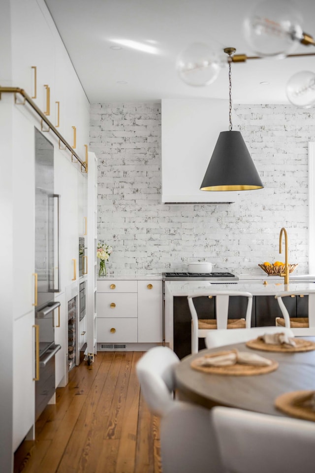 kitchen featuring hanging light fixtures, hardwood / wood-style flooring, and white cabinets