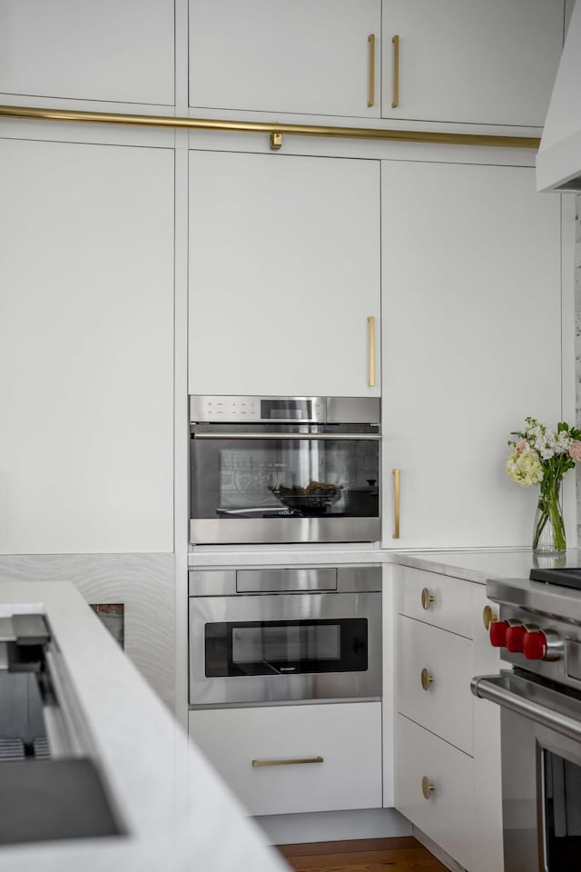 kitchen with white cabinetry, stainless steel appliances, and premium range hood