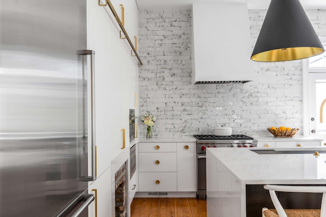 kitchen with high quality appliances, white cabinets, and light hardwood / wood-style floors