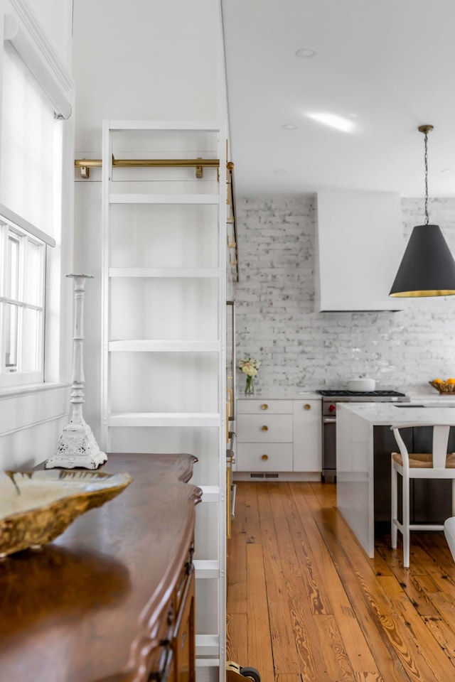 kitchen featuring pendant lighting, decorative backsplash, white cabinets, and light wood-type flooring