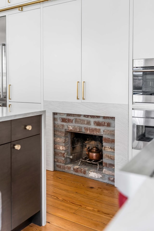 details with light hardwood / wood-style flooring, double oven, a fireplace, and white cabinets