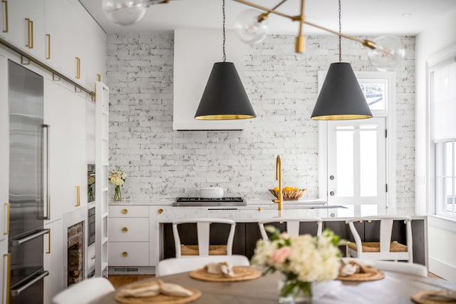 kitchen featuring brick wall, high quality fridge, pendant lighting, wine cooler, and white cabinets