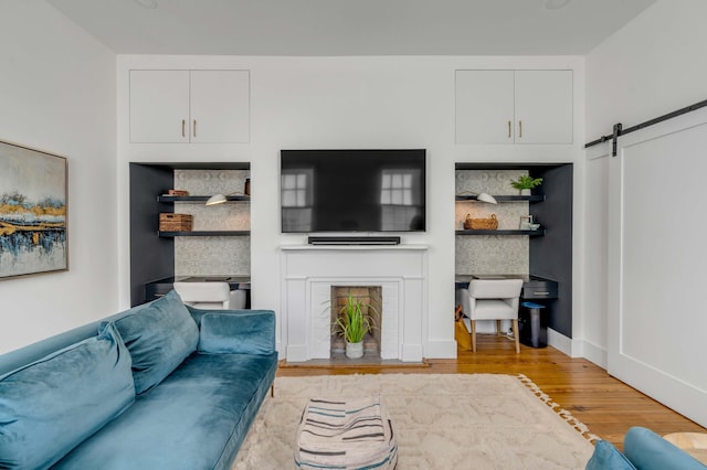 living room with a barn door and light wood-type flooring