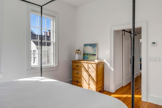 bedroom with hardwood / wood-style flooring and a barn door