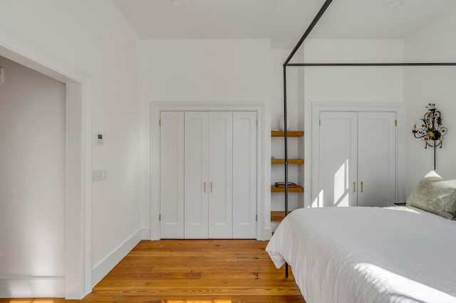 bedroom featuring multiple closets and light wood-type flooring