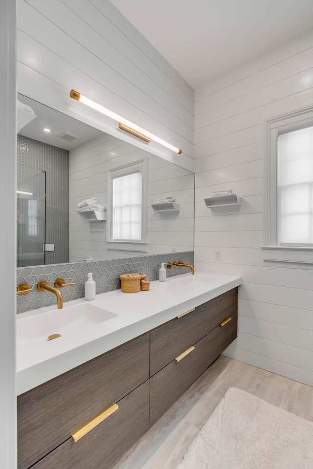 bathroom featuring vanity, wood-type flooring, tasteful backsplash, and a shower