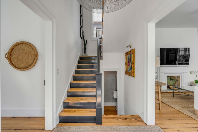 stairs featuring hardwood / wood-style floors and a brick fireplace