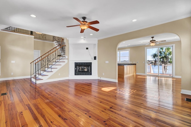 unfurnished living room with stairway, baseboards, hardwood / wood-style floors, and a fireplace