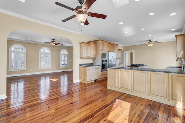 kitchen with a sink, stainless steel appliances, light wood-style floors, crown molding, and baseboards