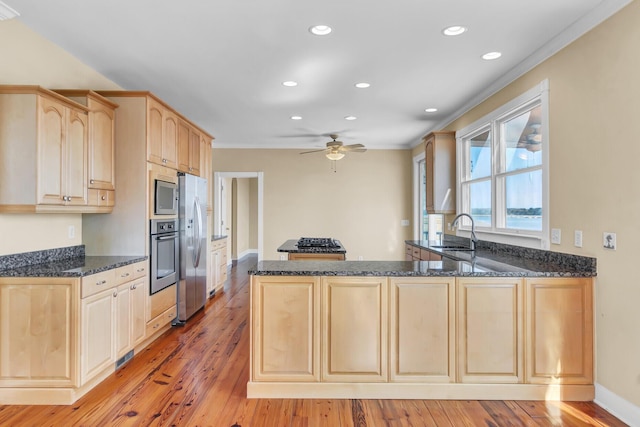 kitchen featuring light brown cabinets, a sink, light wood-style floors, appliances with stainless steel finishes, and a peninsula