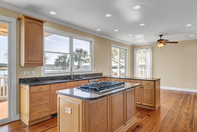 kitchen with a peninsula, light wood-style flooring, a center island, and a sink