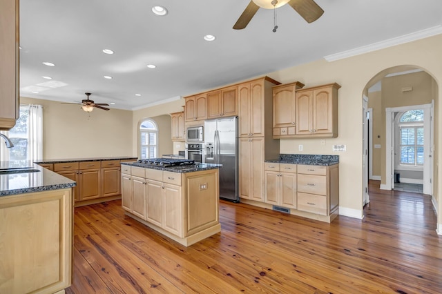 kitchen featuring light brown cabinets, arched walkways, and appliances with stainless steel finishes