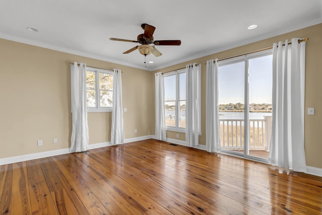 empty room featuring visible vents, baseboards, ornamental molding, and hardwood / wood-style flooring