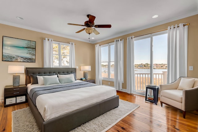 bedroom featuring ceiling fan, ornamental molding, access to exterior, a water view, and light wood-type flooring