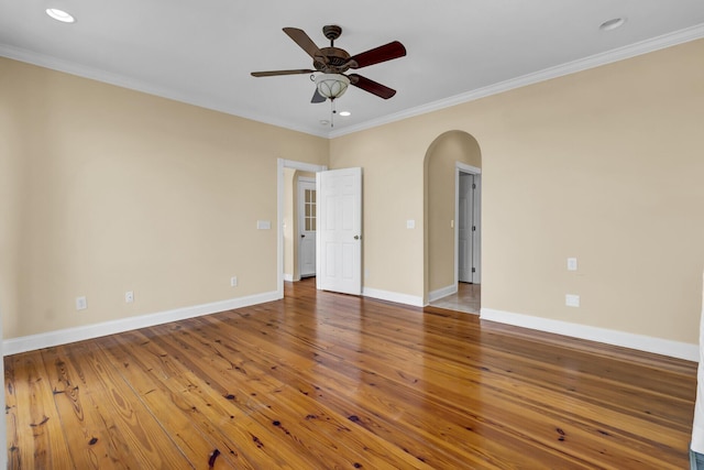 unfurnished room with arched walkways, hardwood / wood-style floors, and crown molding