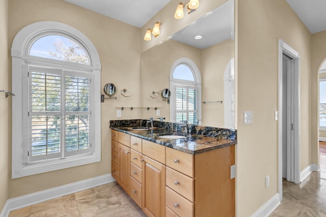 bathroom with double vanity, baseboards, and a sink