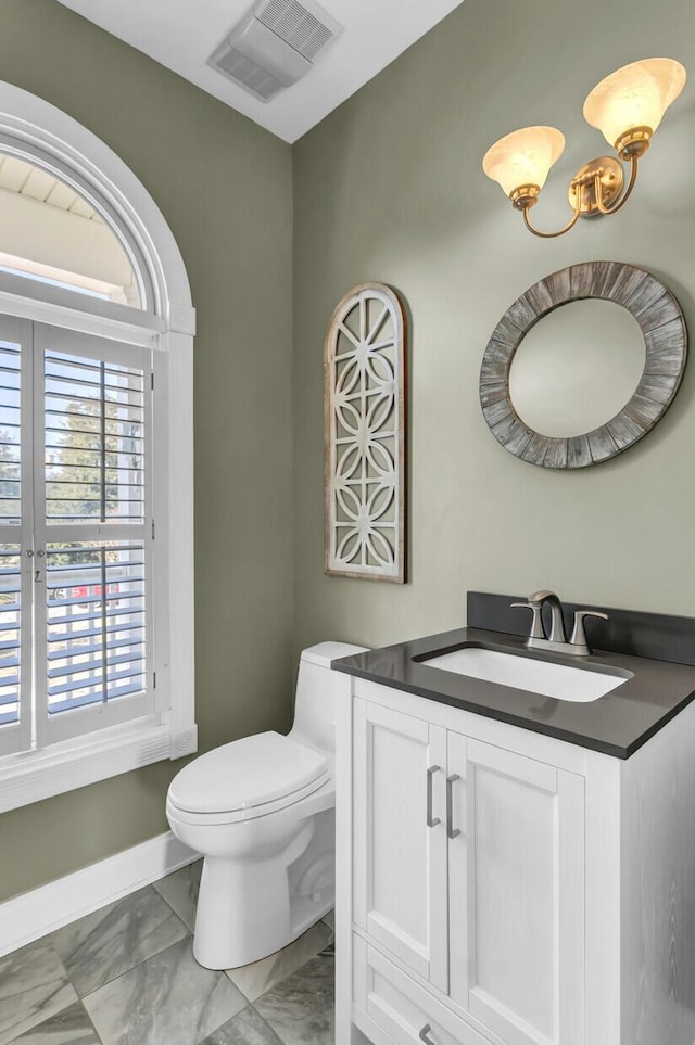 half bathroom featuring visible vents, baseboards, toilet, marble finish floor, and vanity