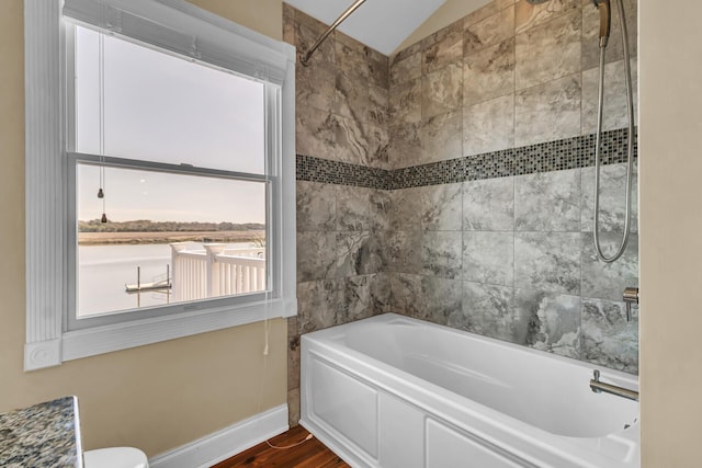 bathroom featuring baseboards, wood finished floors, and vaulted ceiling