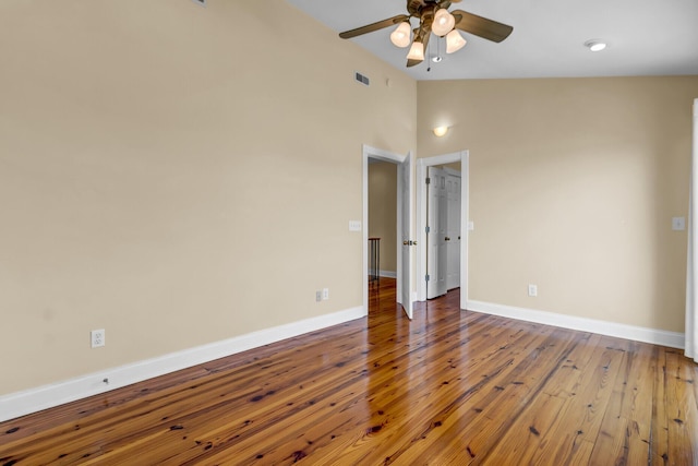 empty room featuring visible vents, lofted ceiling, wood-type flooring, baseboards, and ceiling fan