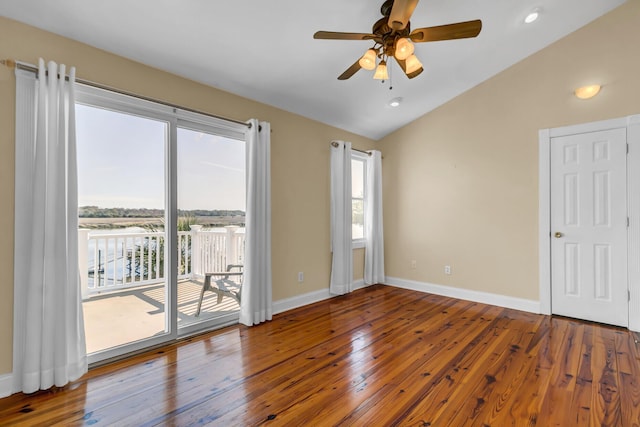 unfurnished room featuring hardwood / wood-style floors, vaulted ceiling, a healthy amount of sunlight, and baseboards