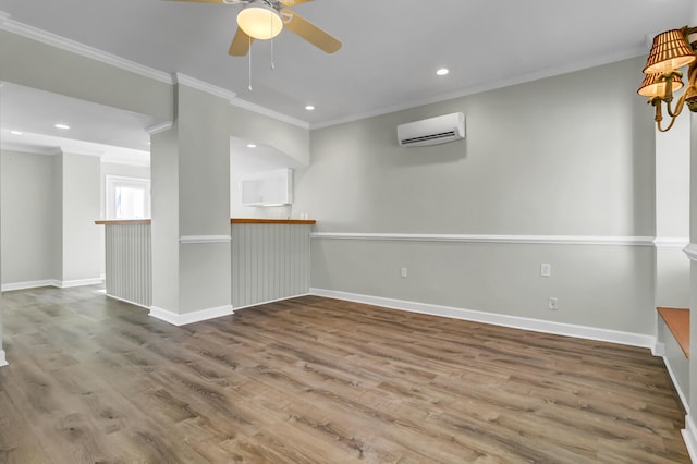 empty room with ornamental molding, an AC wall unit, baseboards, and wood finished floors