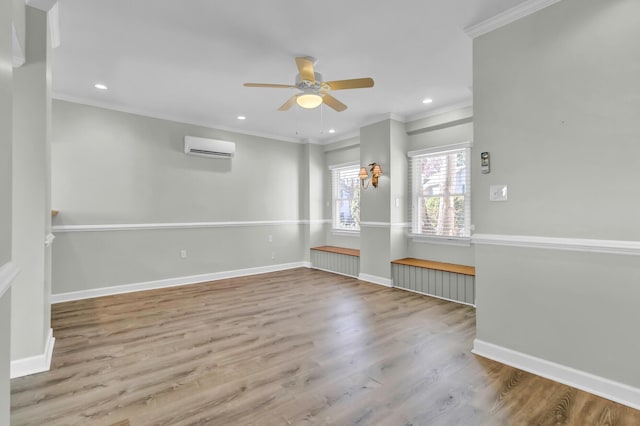 unfurnished room featuring a wall mounted air conditioner, baseboards, wood finished floors, and crown molding