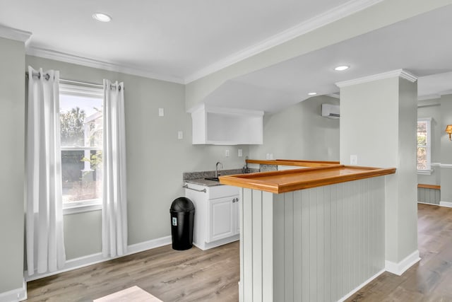 kitchen featuring white cabinetry, crown molding, light wood finished floors, and a wall mounted AC