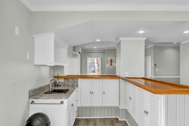 kitchen with ornamental molding, a sink, wood finished floors, white cabinetry, and recessed lighting